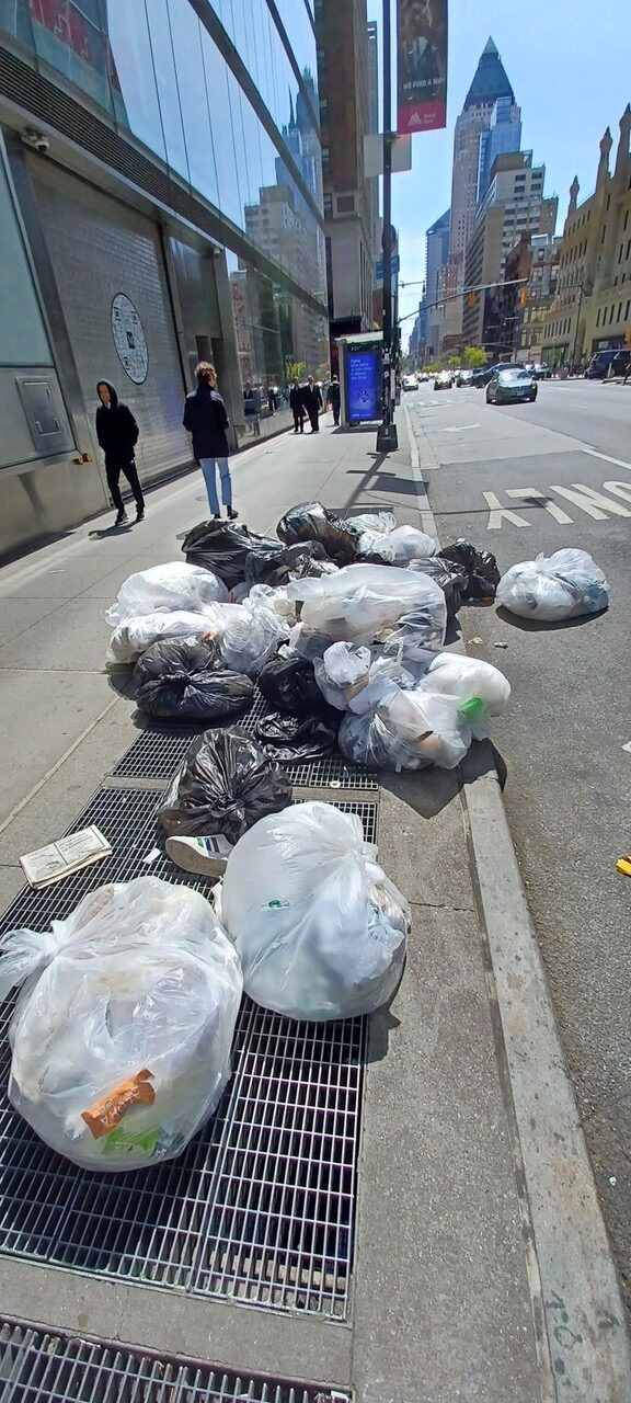 Collection day. Bags wait on the sidewalk until the truck comes.
